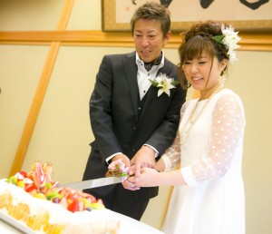 新婦妹さん手作りのウェディングケーキに笑顔で入刀する新郎新婦