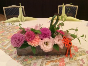 ゲストの席には、淡いオレンジ～やわらかなピンクを基調にグリーンで軽やかに演出したお花を