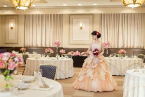 モダンクラシカルな会場に白のテーブルクロスとピンクのお花をコーディネート。花嫁も優しい色合いのドレスに赤のブーケと髪飾りを合わせてとっても上品