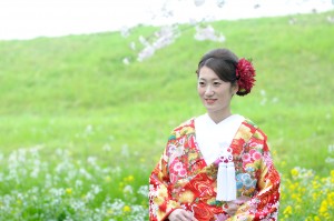 鮮やかなグリーンと菜の花をバックにたつ新婦