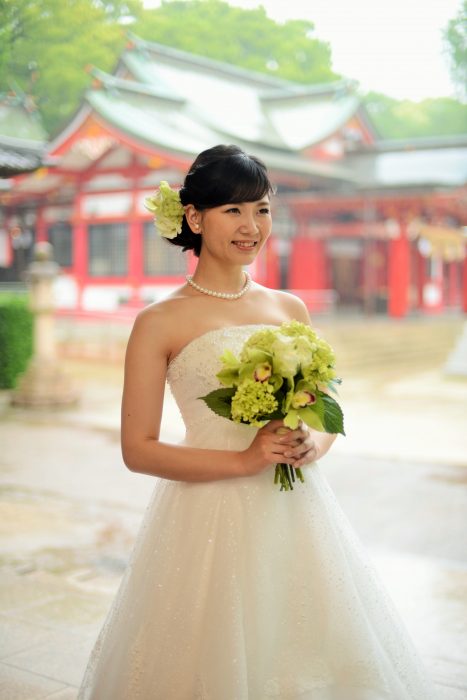 春日神社本殿をバックに、ウェディングドレス姿の花嫁がカレに微笑む